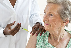 Elderly woman being vaccinated by healthcare professional.